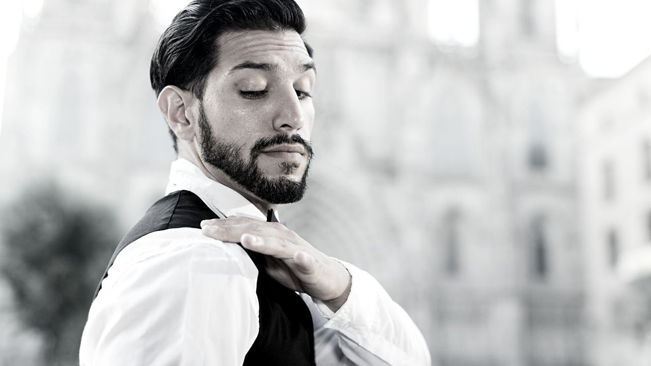 Man in shirt and waistcoat dusting of his shoulder